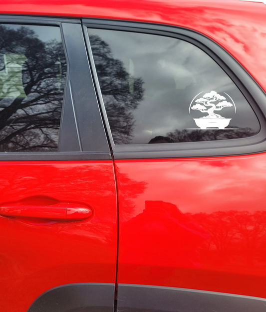 Red car with a bonsai tree decal on the window