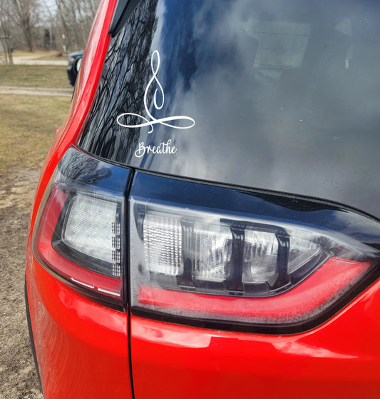 Red car with a white decal on the back window that reads 'Breathe'.