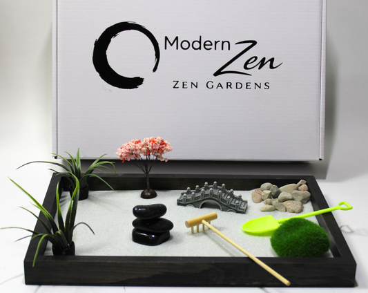 Zen garden setup with rocks, plants, and tools on a tray with 'Modern Zen' branding in the background.