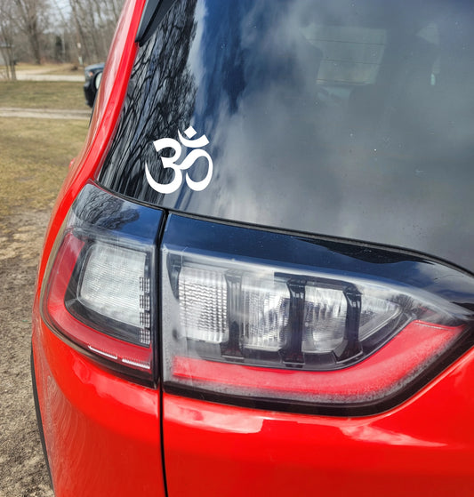 Red car with a white Om symbol decal on the rear window.