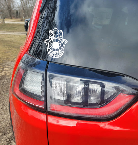 White Hamsa hand decal on a red car's back window.