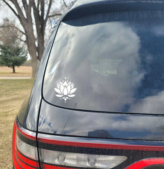 Car window with a white lotus flower decal outdoors